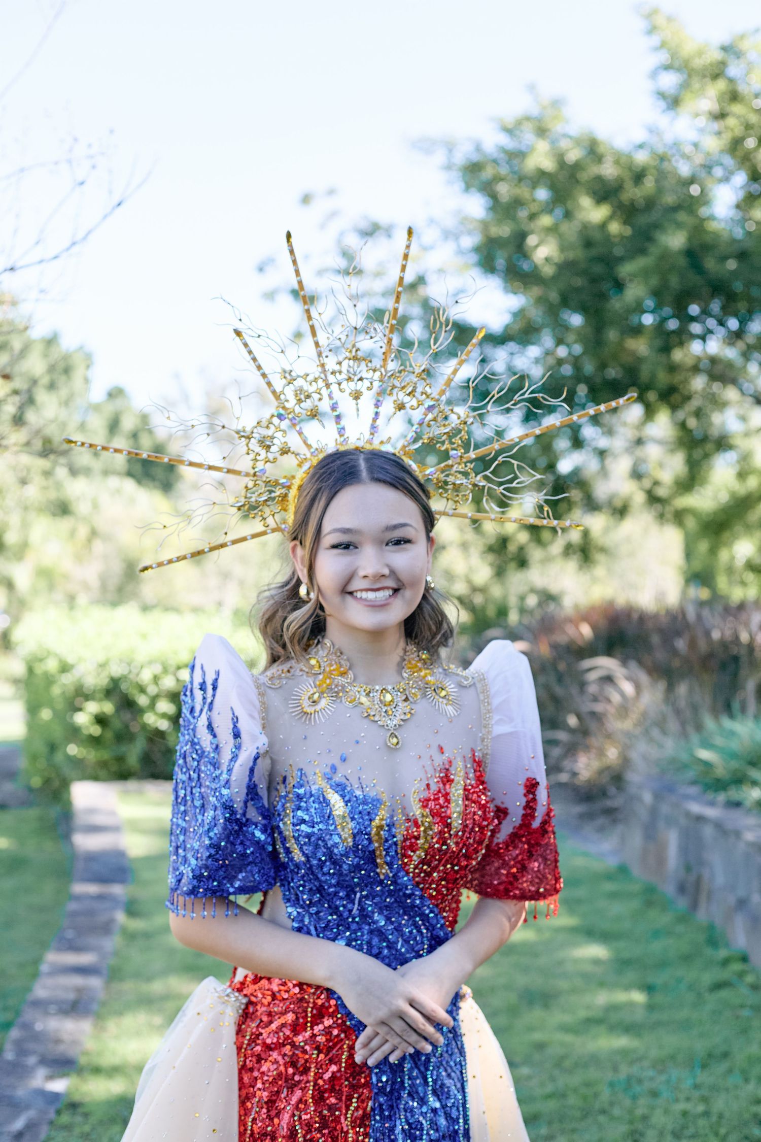 A portrait of a woman wearing a blue and red patterned dress, posing outdoors.