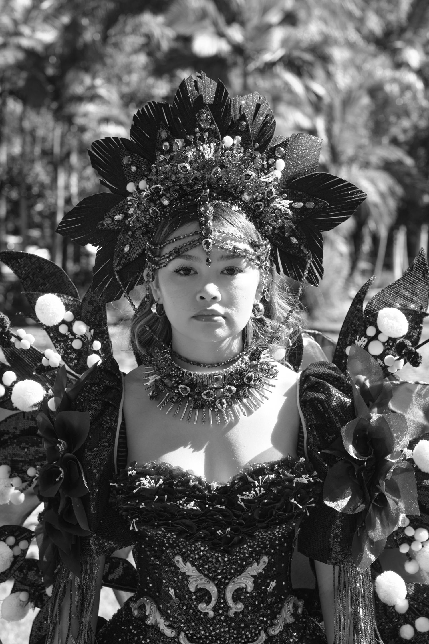 A monochrome portrait of a woman wearing an elaborate feathered headpiece.