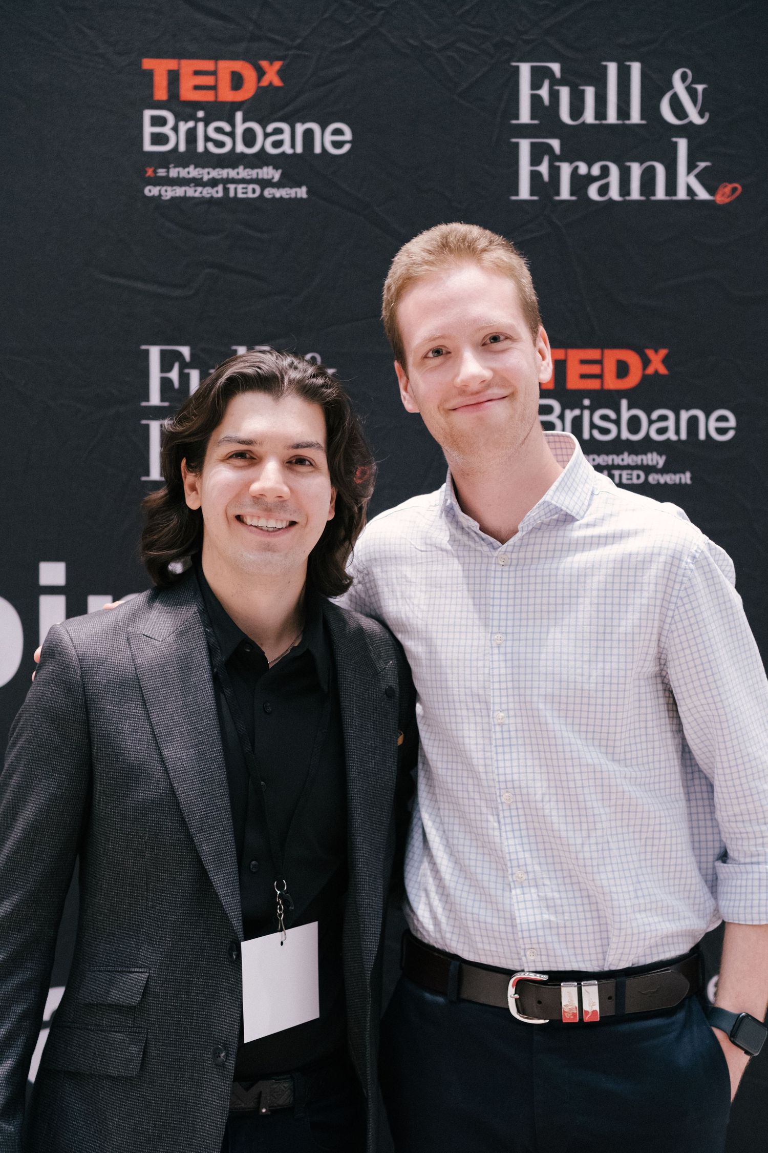 Two men smiling at TEDx Brisbane event backdrop with Full & Frank sponsorship signage.