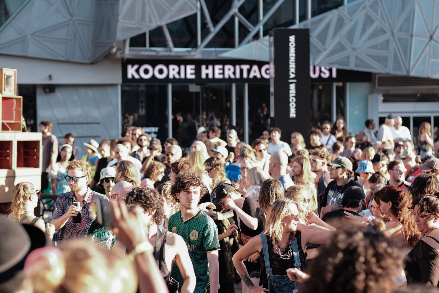 Large crowd gathered outside Koorie Heritage Trust building at an outdoor festival event.
