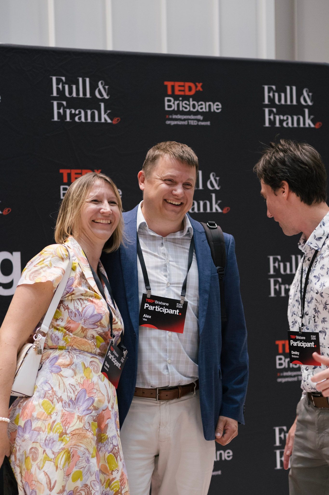 Three TEDx Brisbane participants laughing and networking in front of a Full & Frank branded backdrop at an event.