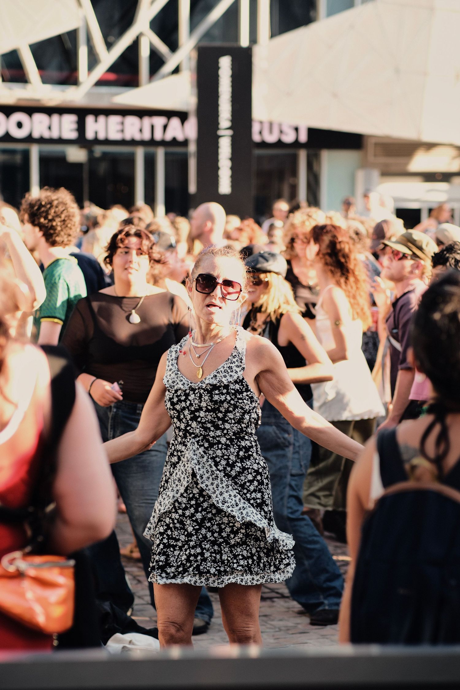Woman in floral dress dancing at outdoor festival crowd near Koorie Heritage Trust.