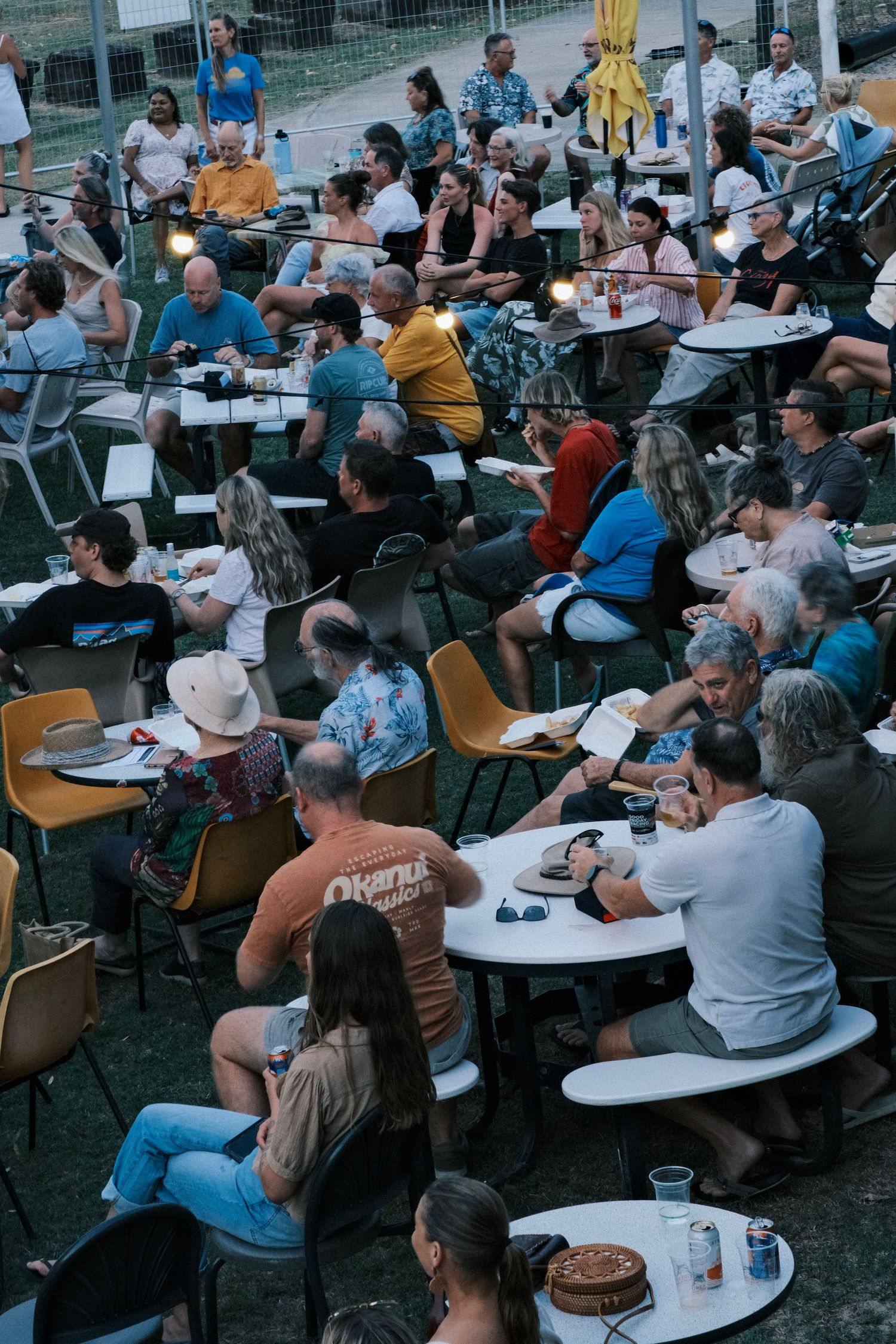 A high-angle view of a crowd of people dining at tables outdoors.