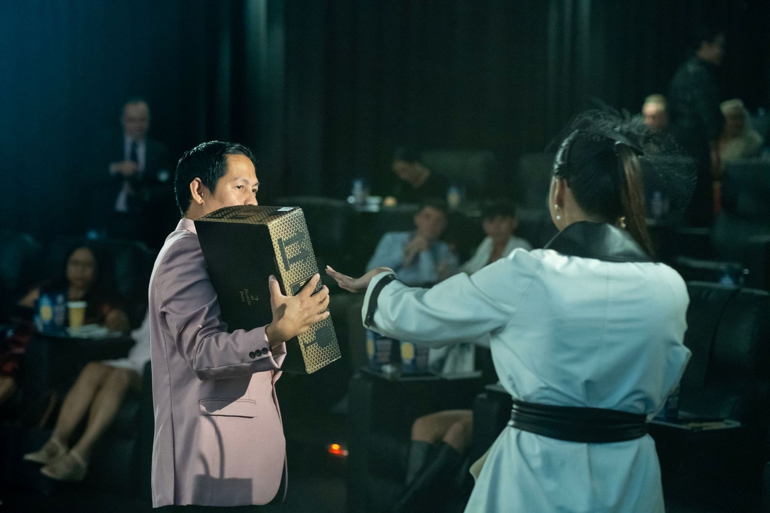 A person presenting a box to another individual during a stage event.