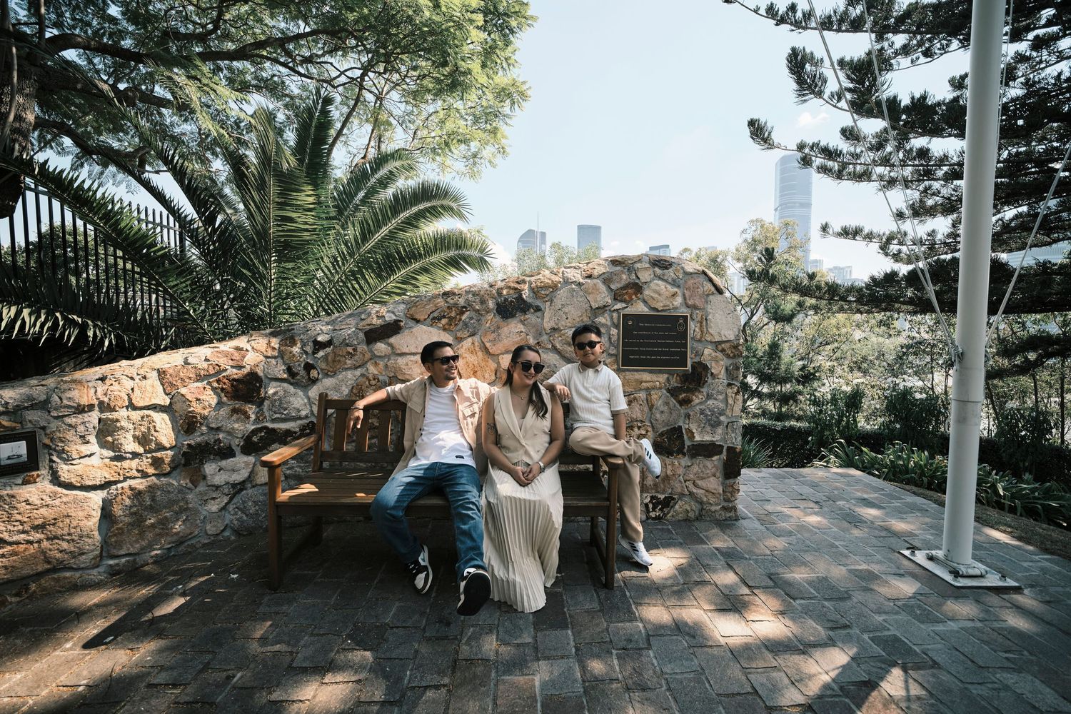 A family of three sitting and posing in front of a stone church building.