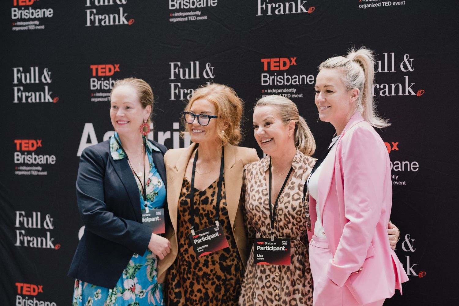Four women posing together smiling at TEDx Brisbane Full & Frank event backdrop.