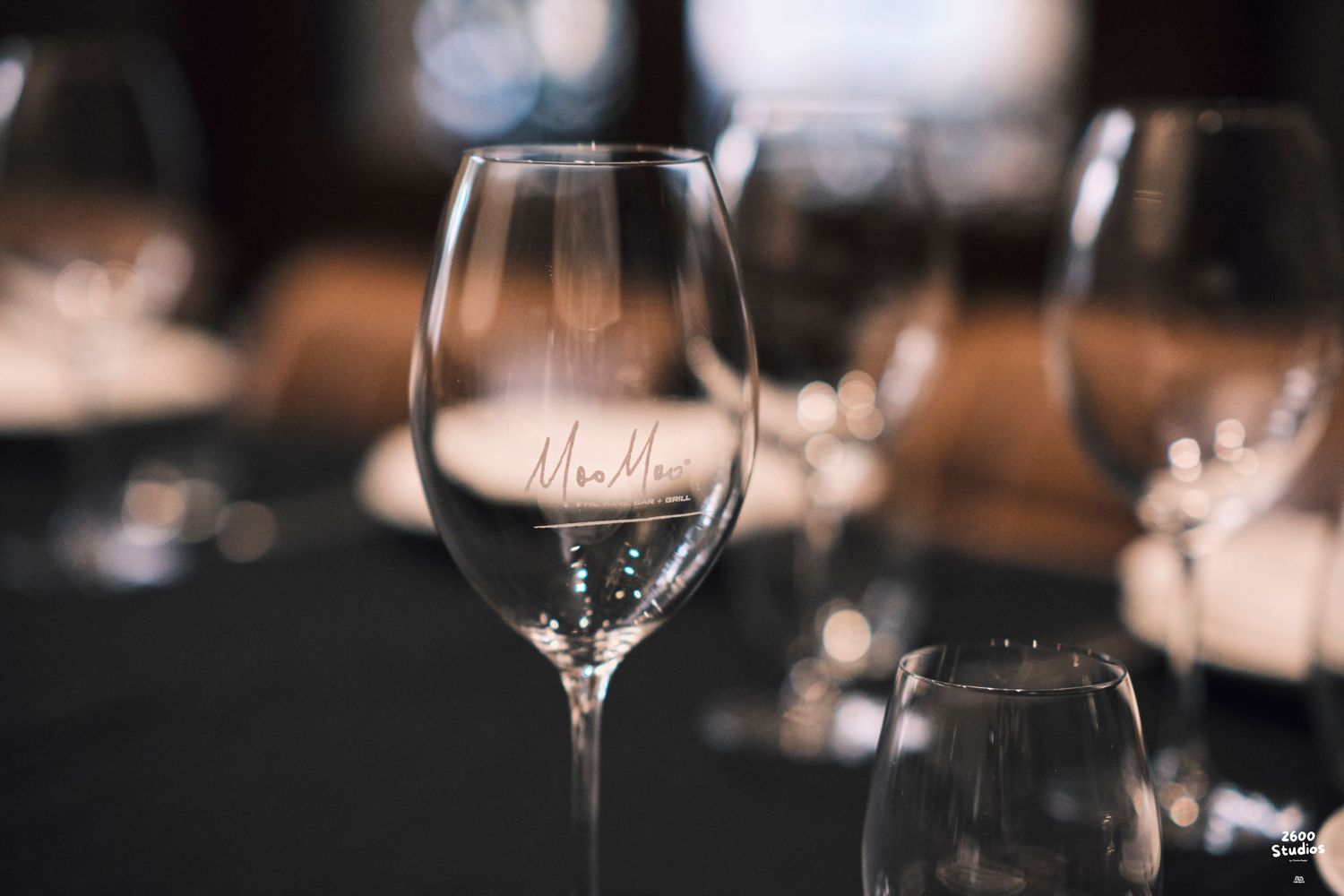 Close-up of an engraved wine glass at an elegant dark-themed restaurant table setting.