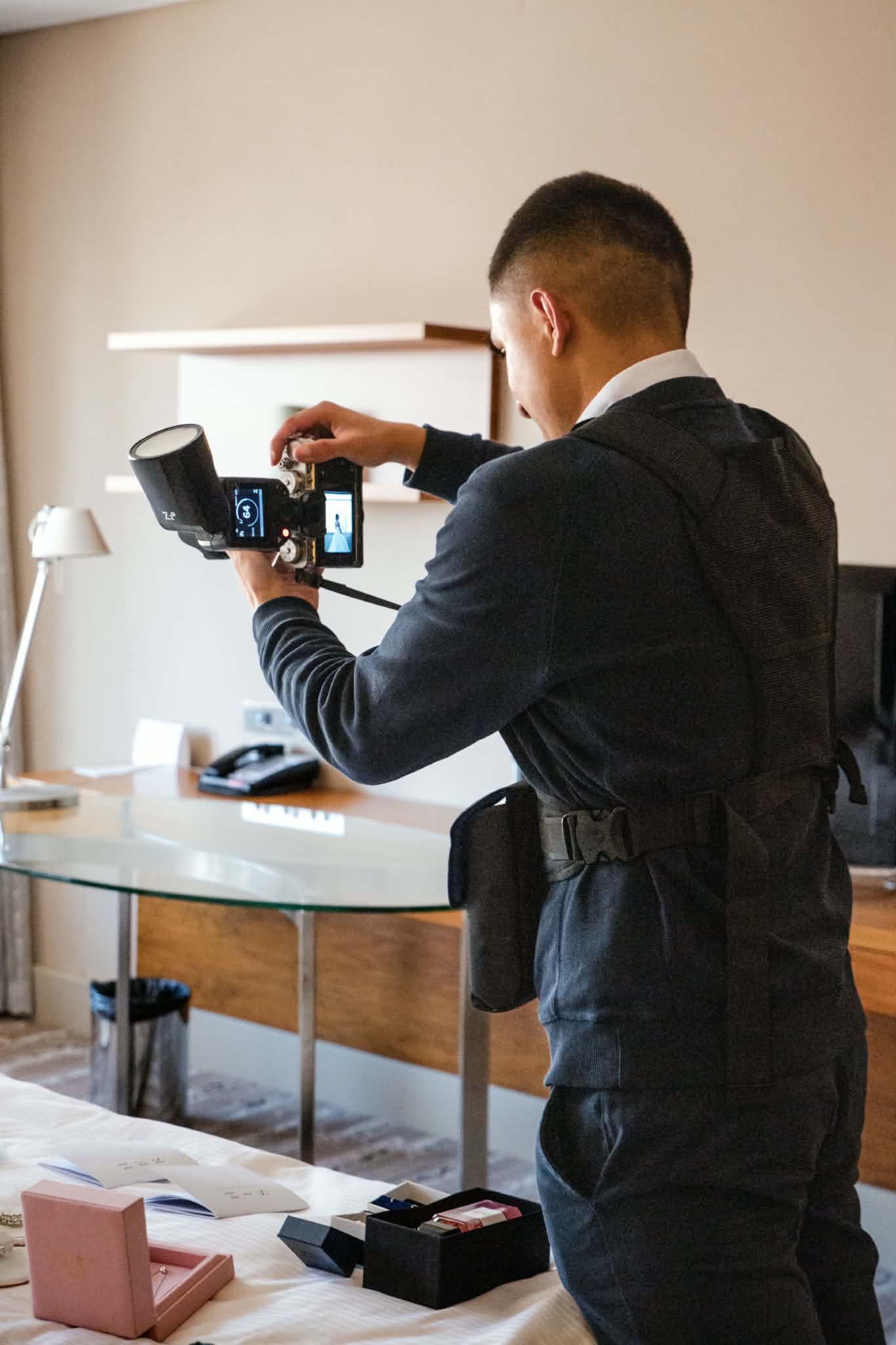 Photographer adjusting professional studio flash equipment in a hotel room before a wedding shoot.