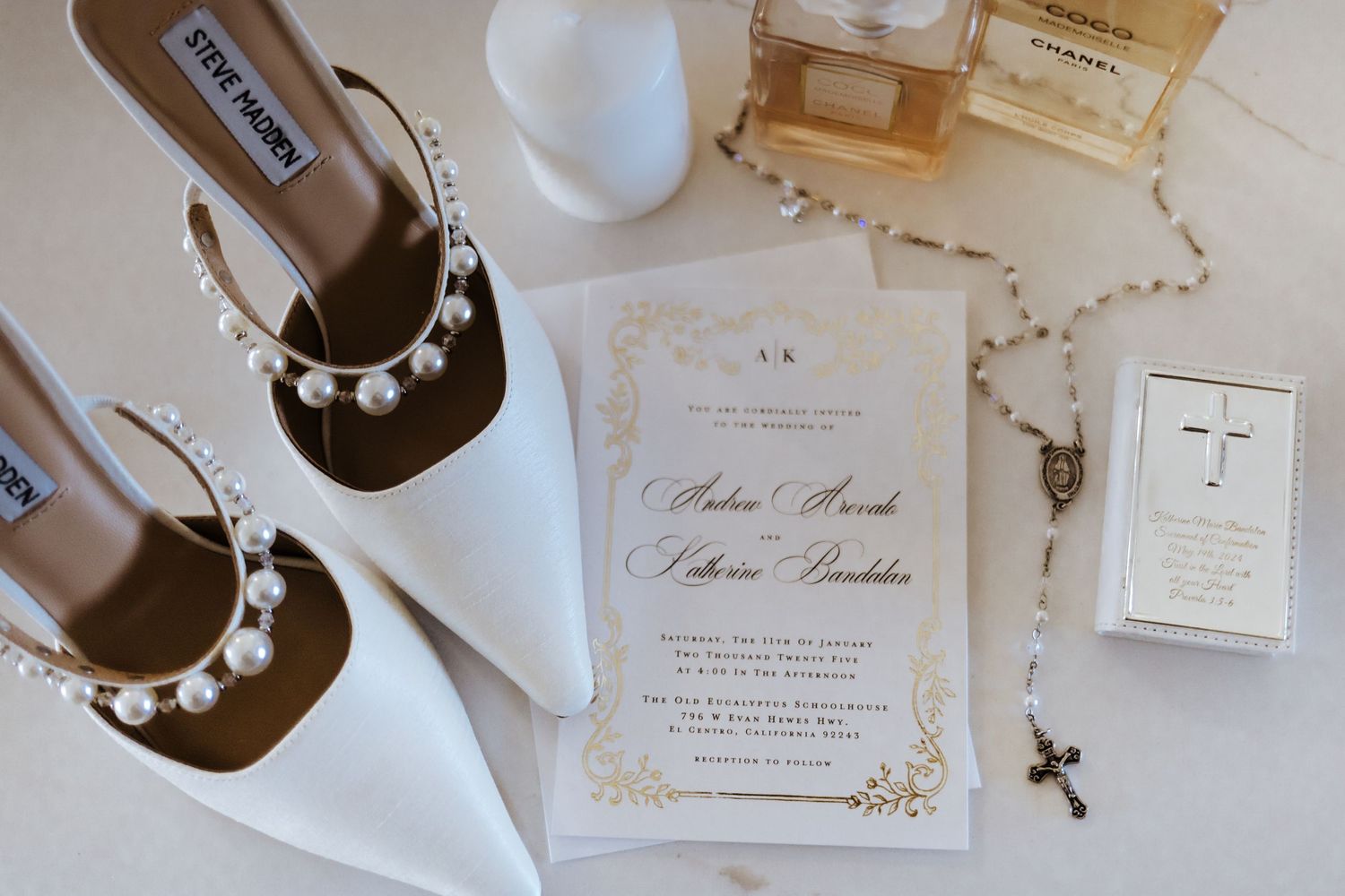Wedding flat lay featuring Steve Madden pearl heels, gold invitation, rosary, Chanel perfume, and cross card.