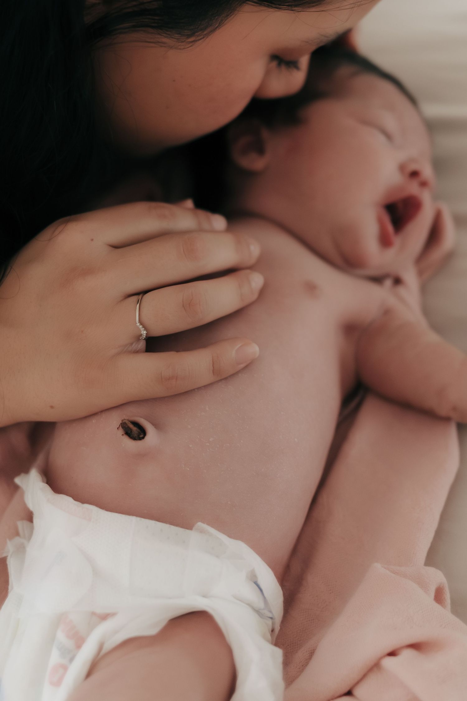 Mother tenderly kissing her newborn baby while gently cradling the infant in her arms.