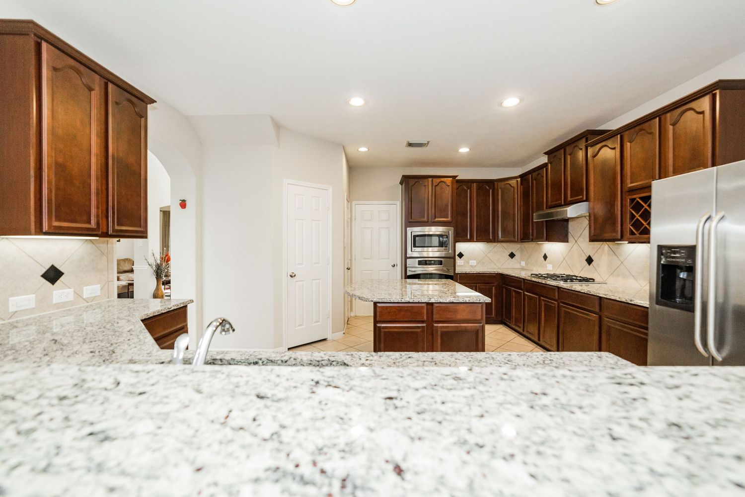 Spacious kitchen with rich cherry cabinets, granite countertops, and stainless steel appliances.