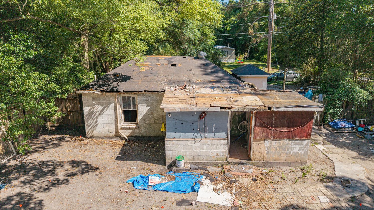 Aerial view of a severely dilapidated house with damaged roof, crumbling walls, and debris scattered around the neglected property.