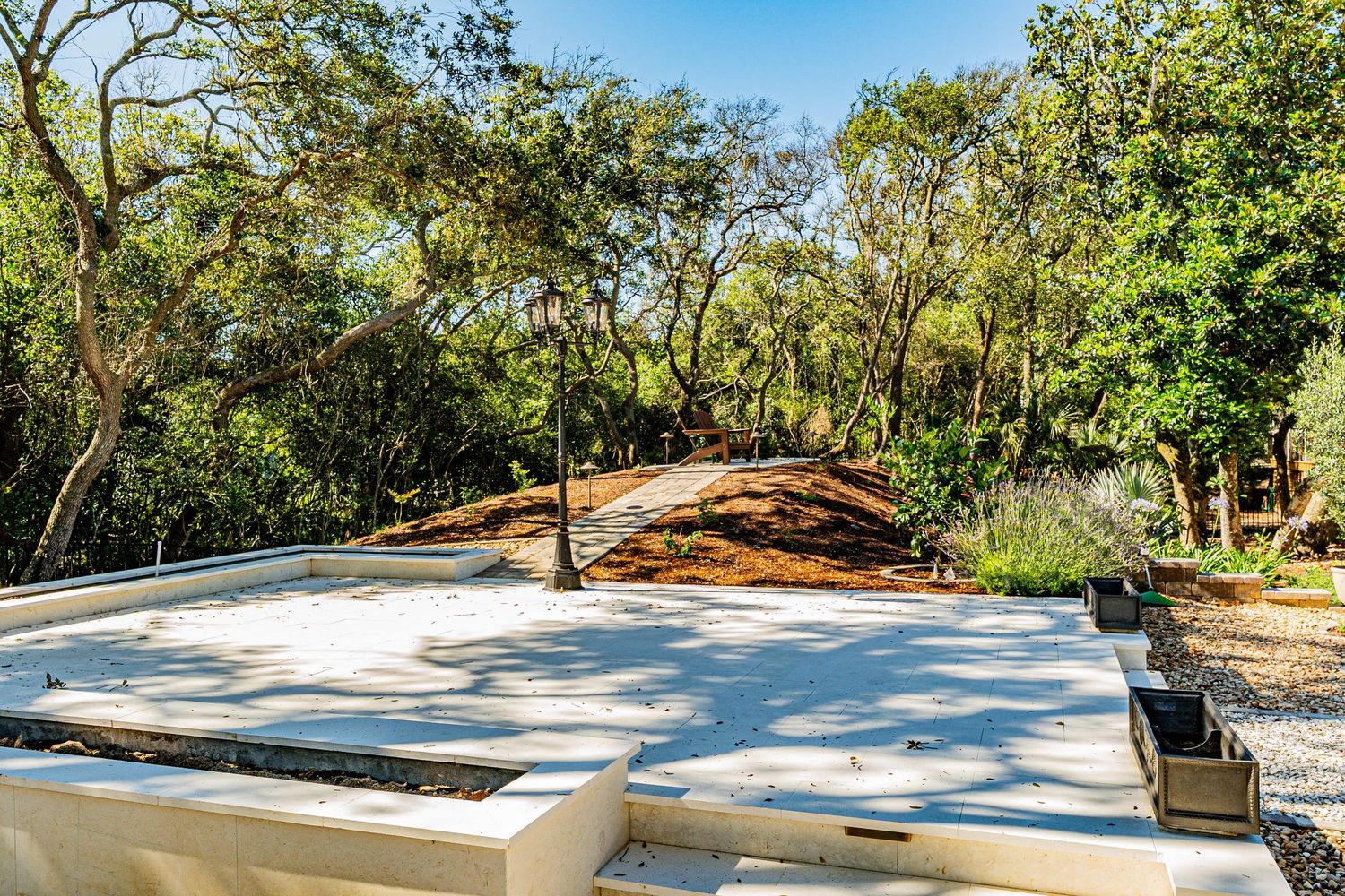 Concrete foundation slab surrounded by lush oak trees and natural landscaping on a sunny day.