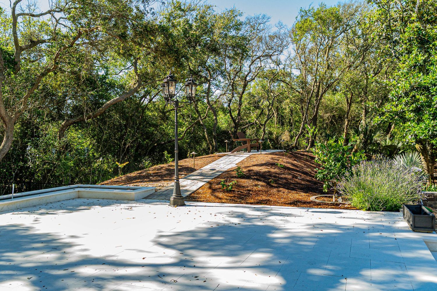 Rooftop terrace overlooking a lush green garden with mature trees, a pathway, and landscaped grounds.