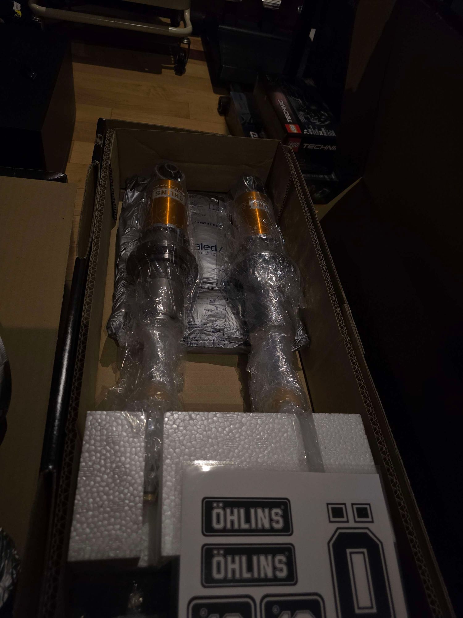 Ohlins performance coilover suspension kit unboxed showing gold shock absorbers in packaging.