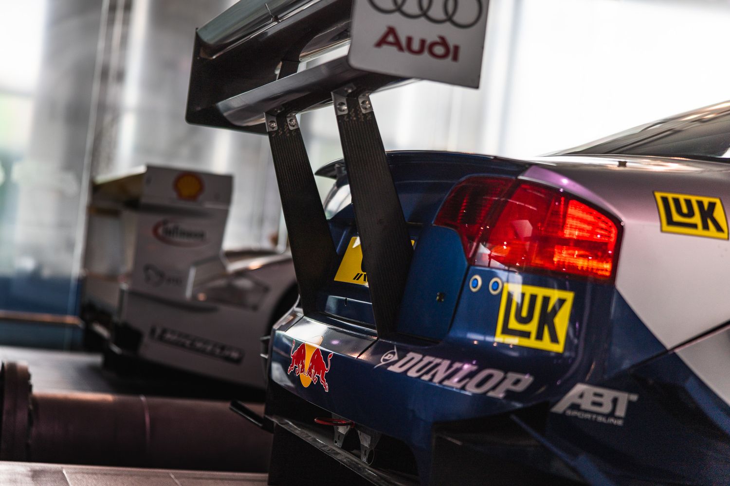 Close-up rear view of an Audi DTM racing car showing spoiler, Red Bull and Dunlop sponsor logos.