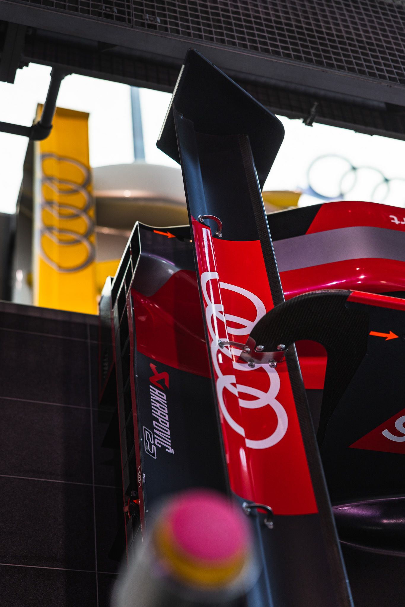 Red and black Audi Formula 1 car rear wing detail with four-ring logo visible.