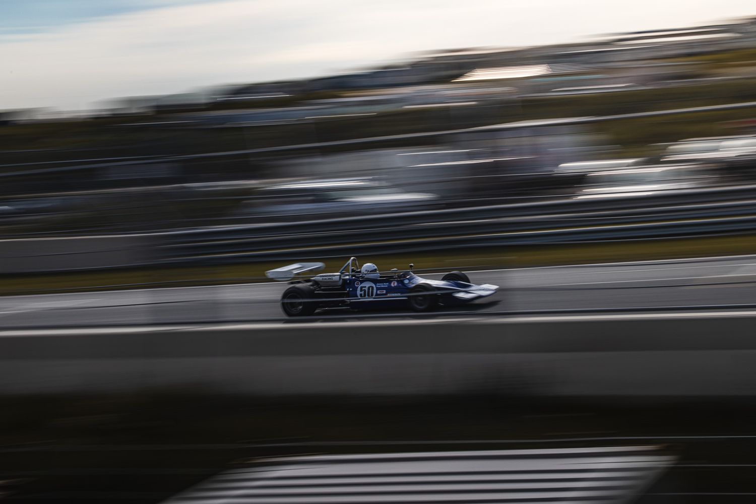Vintage Formula racing car speeding along a track with motion blur background.
