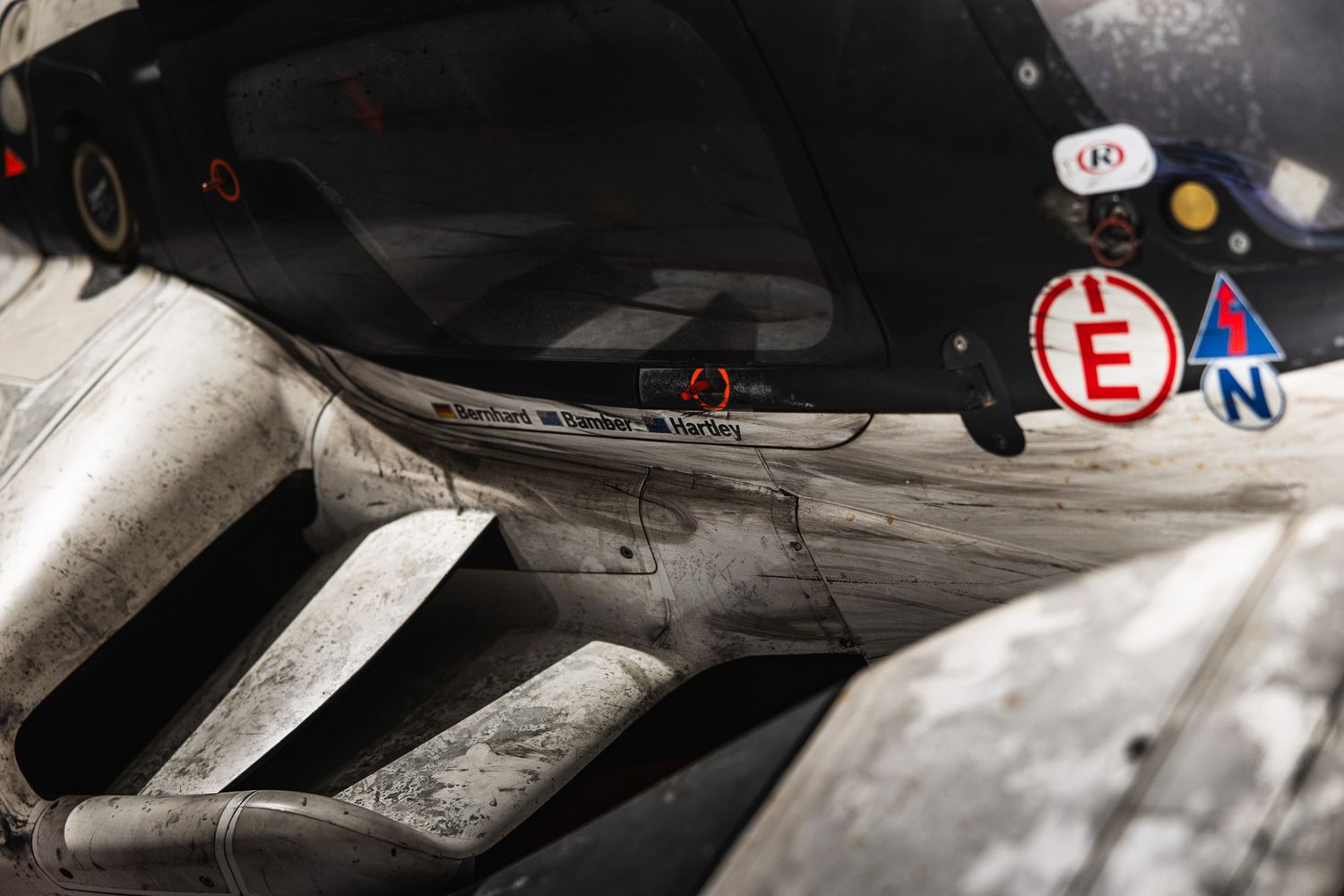 Close-up detail of a battle-worn racing car cockpit with navigation stickers and worn bodywork.