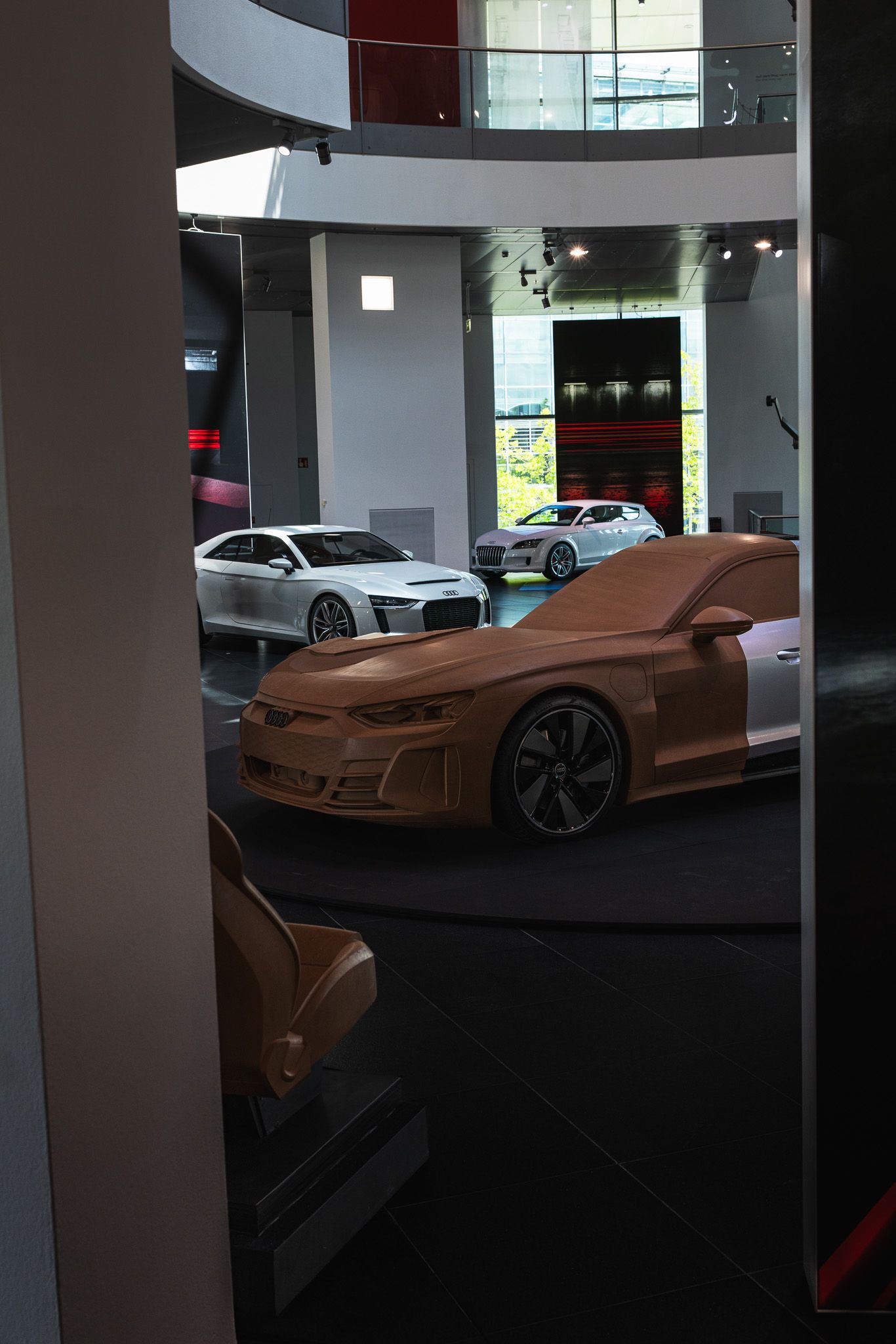 Clay model prototype cars on display inside a modern automotive design studio.