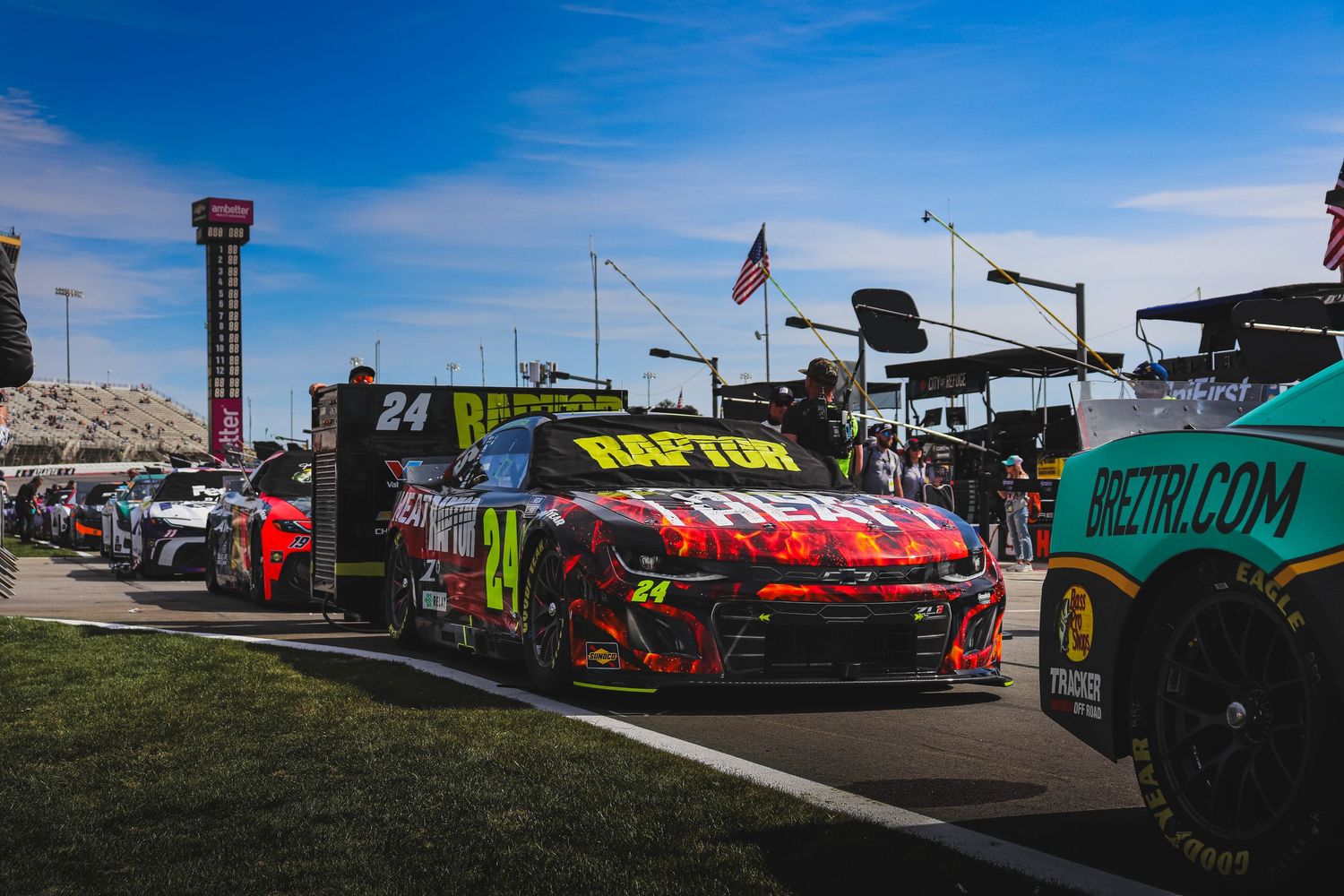 NASCAR race car number 24 with colorful livery lined up in pit lane at a racing event.