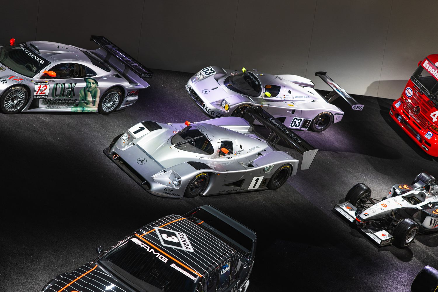Collection of historic racing cars including Le Mans prototypes displayed in a motorsport museum.