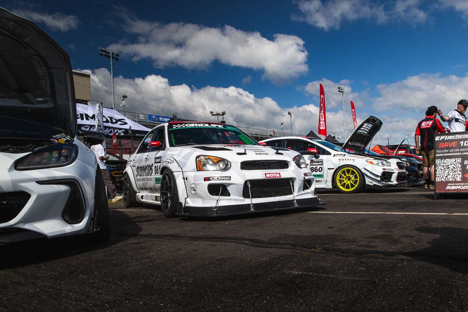 Modified white Subaru Impreza WRX STI drift car displayed at an outdoor motorsport event.
