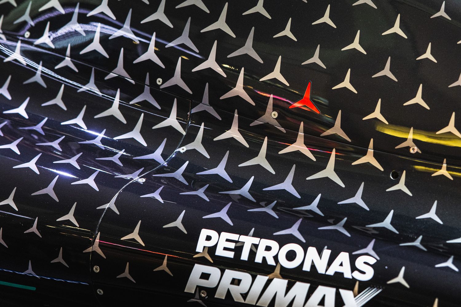 Close-up of a Petronas Primax branded surface covered with silver Mercedes-Benz star logos pattern.