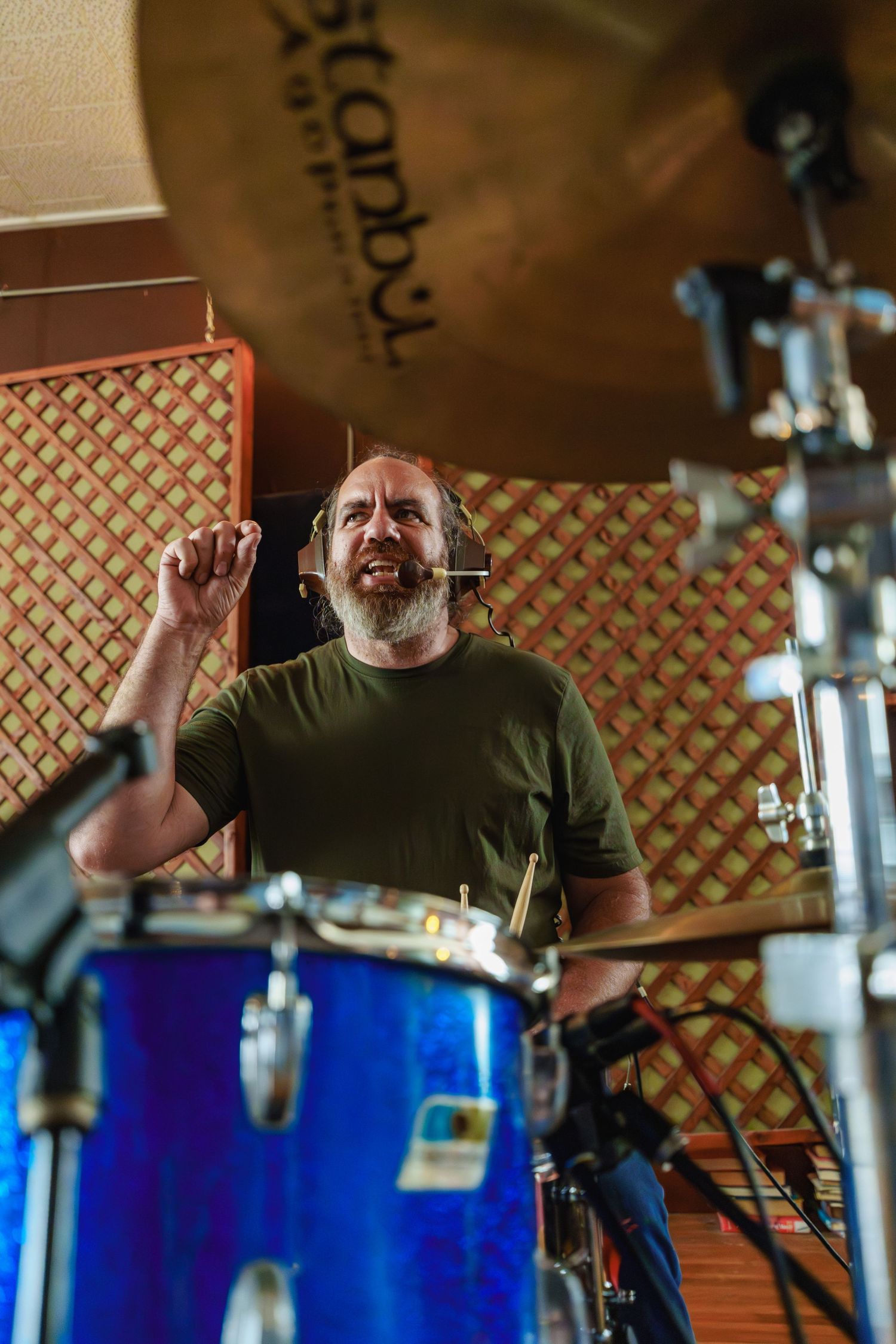 Bearded drummer laughing behind a blue drum kit with Istanbul cymbals in a recording studio.