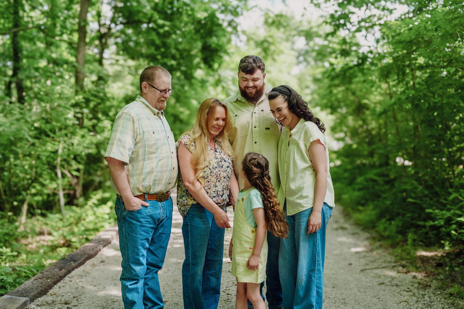 Family of five sharing a warm moment together on a scenic forest path.