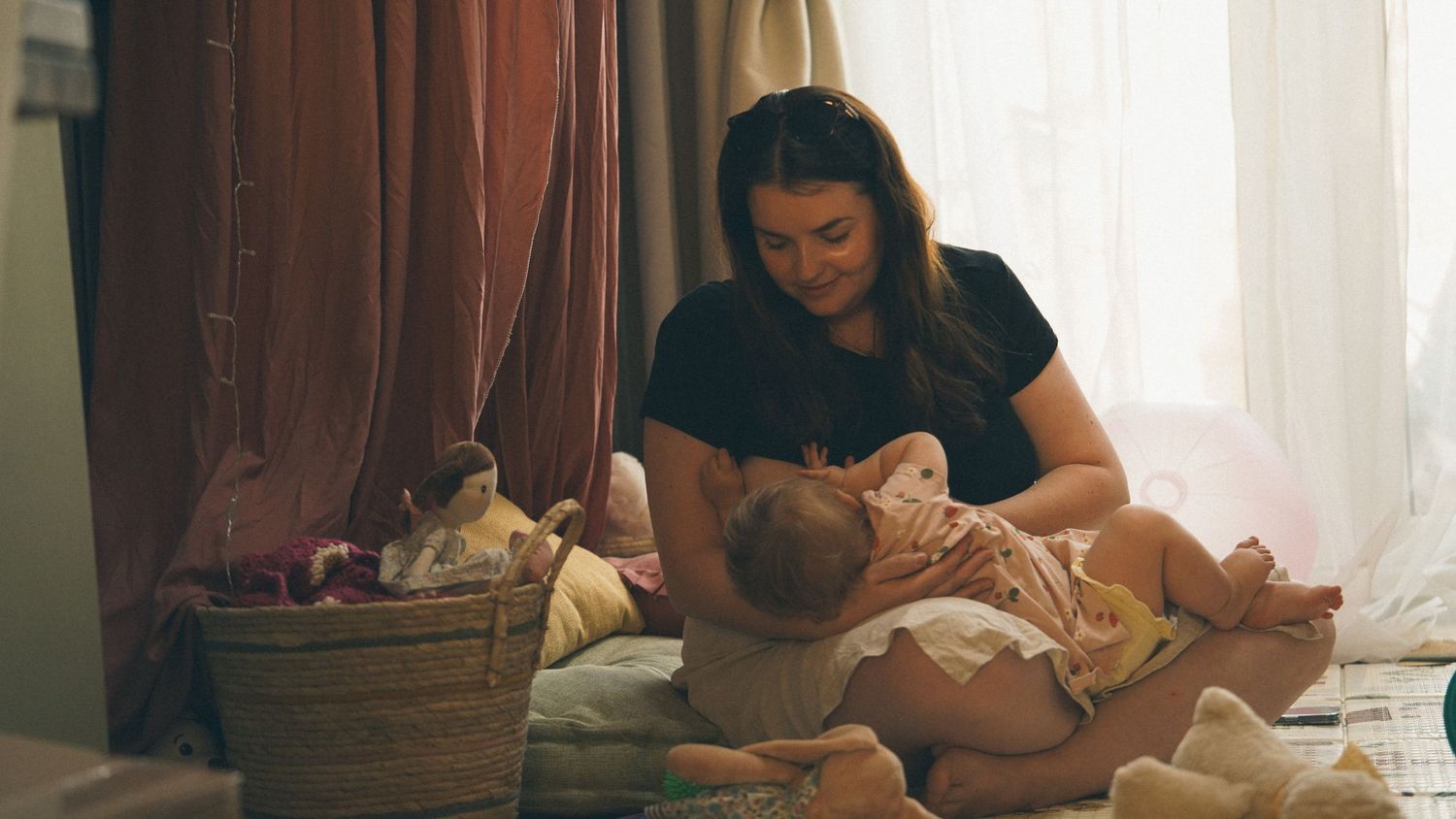 Natural light, at home photography session with mother and baby. Mother is feeding baby, in Suffolk.