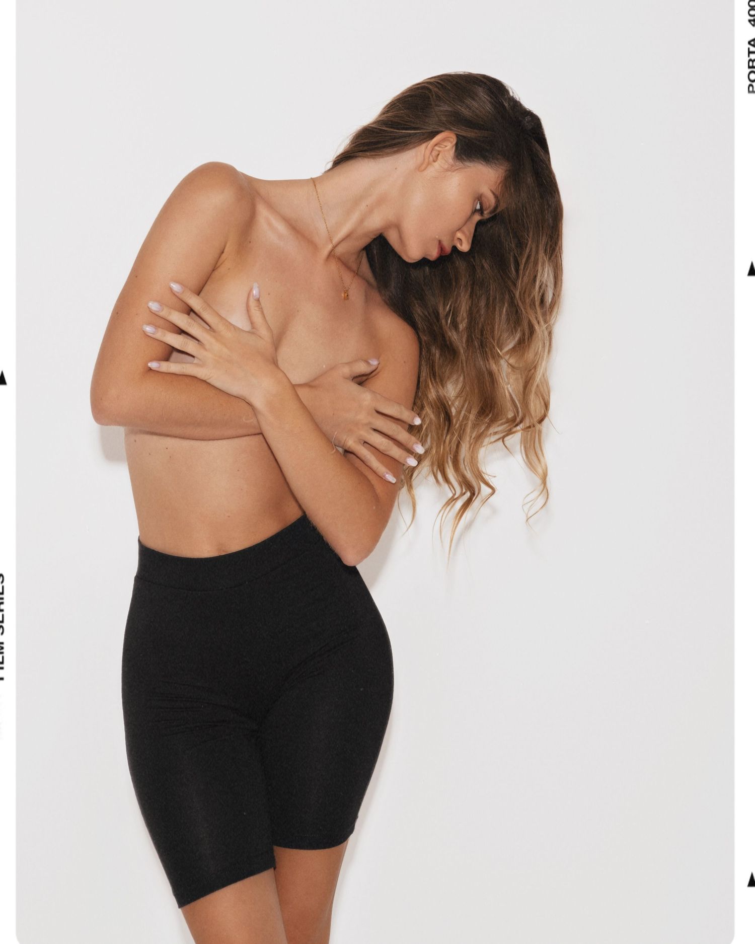 Woman wearing black high-waisted bike shorts, posing with arms crossed over chest, showcasing shapewear fit and coverage.
