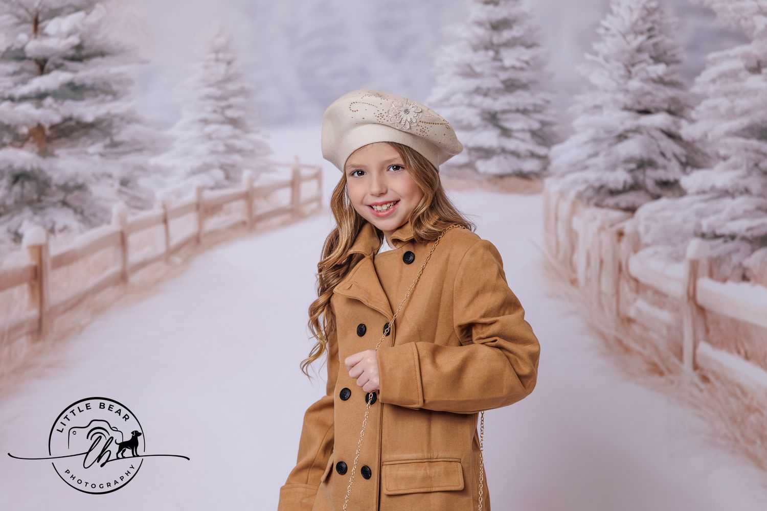 Smiling girl wearing tan beret and brown double-breasted coat in a winter snow scene backdrop.