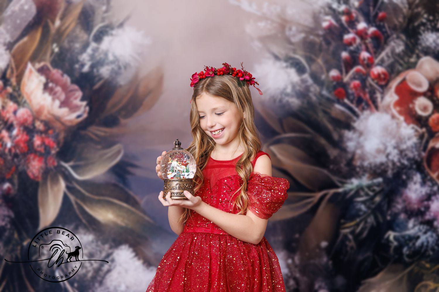 A smiling girl in a red dress and floral crown holds a glowing snow globe against a floral backdrop.