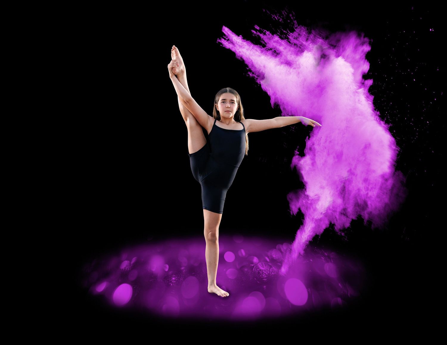 Gymnast performs standing split pose enveloped in purple powder cloud on dark background.