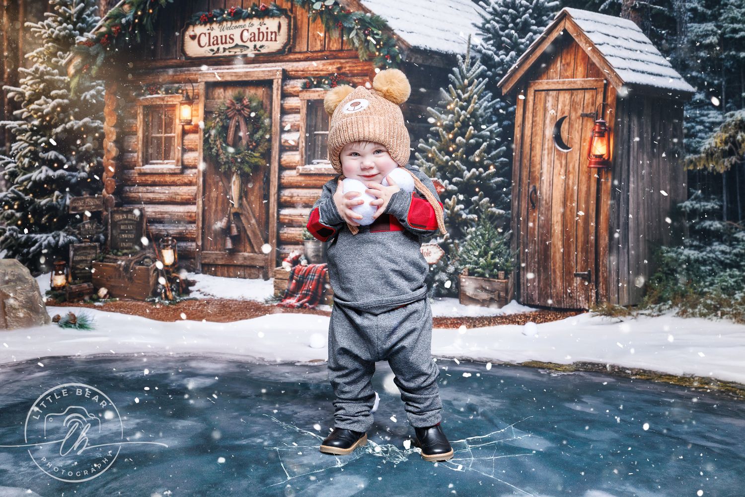 Toddler in winter outfit stands on ice skates before a snowy cabin backdrop with falling snow.