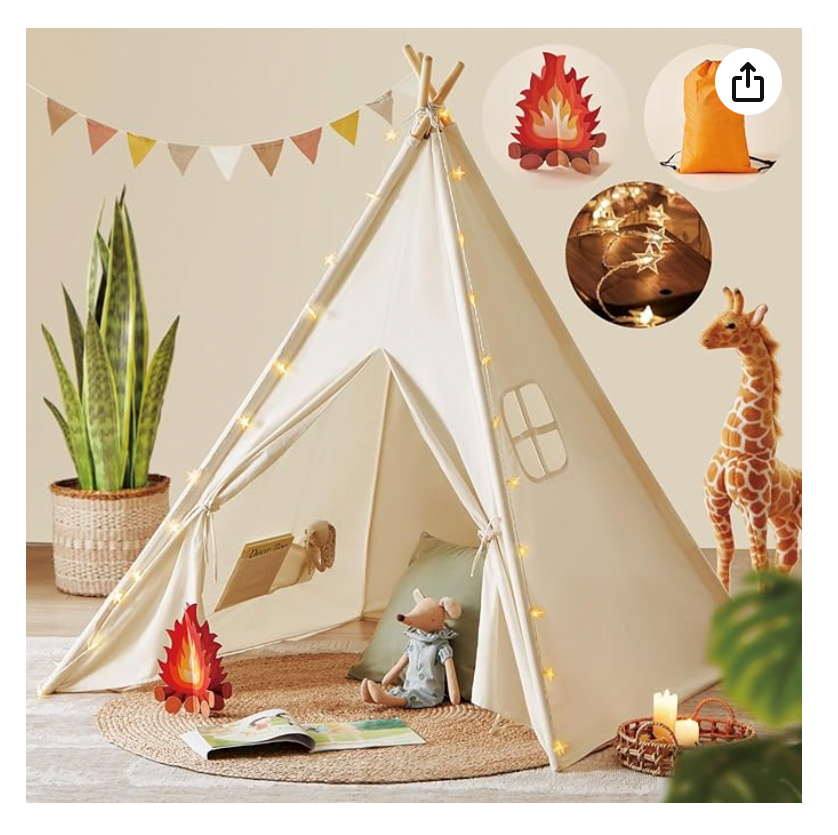 A white canvas kids teepee tent with fairy lights, toy giraffe, and campfire decorations in a cozy playroom setting.