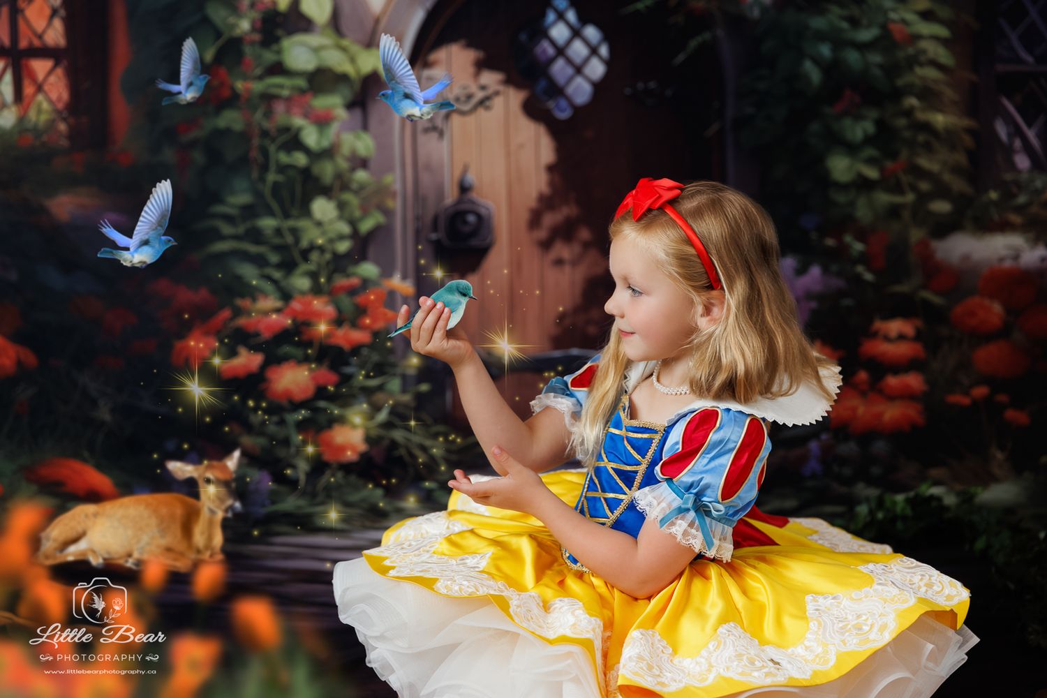 Girl in Snow White costume holds a blue butterfly in a magical fairy tale garden setting with deer and birds.