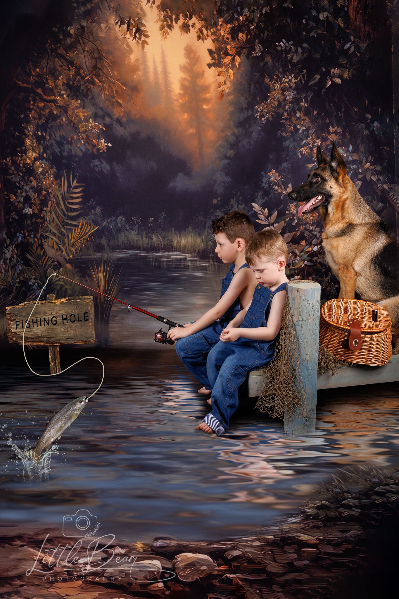 Two boys in denim overalls fishing at a woodland hole with a German Shepherd and wicker basket nearby.