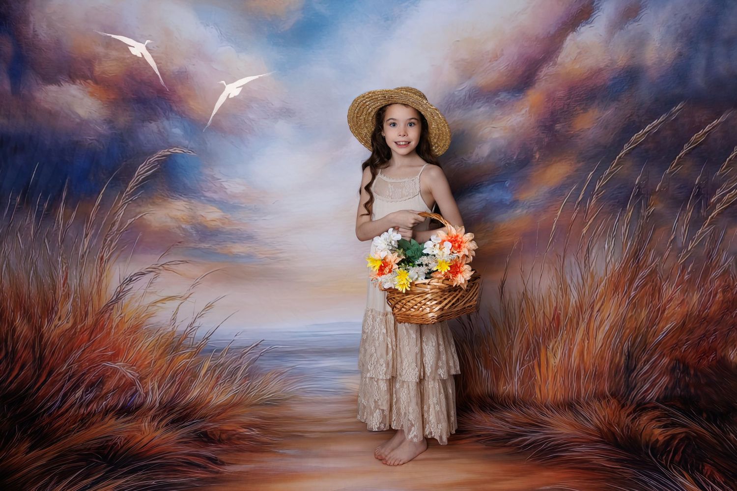 A young girl in a lace dress and straw hat holds a flower basket in front of a painted coastal landscape backdrop.