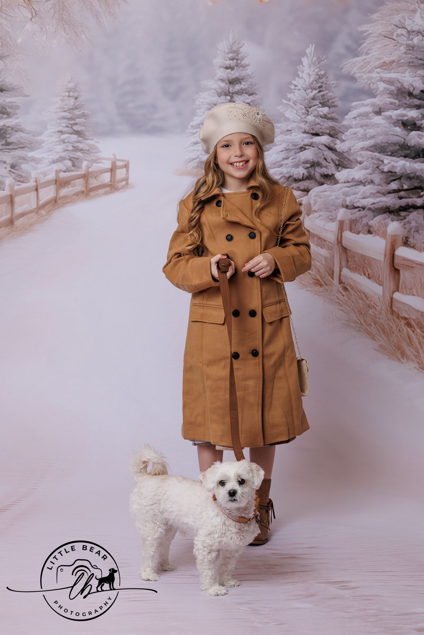 Young girl in brown coat and cream beret poses with white fluffy dog in snowy winter photography studio backdrop.