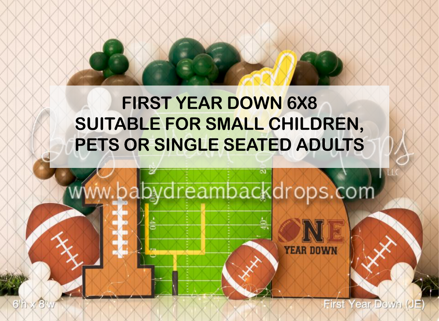 Football-themed first birthday party backdrop with ONE YEAR DOWN text, footballs, and green balloons for photos.