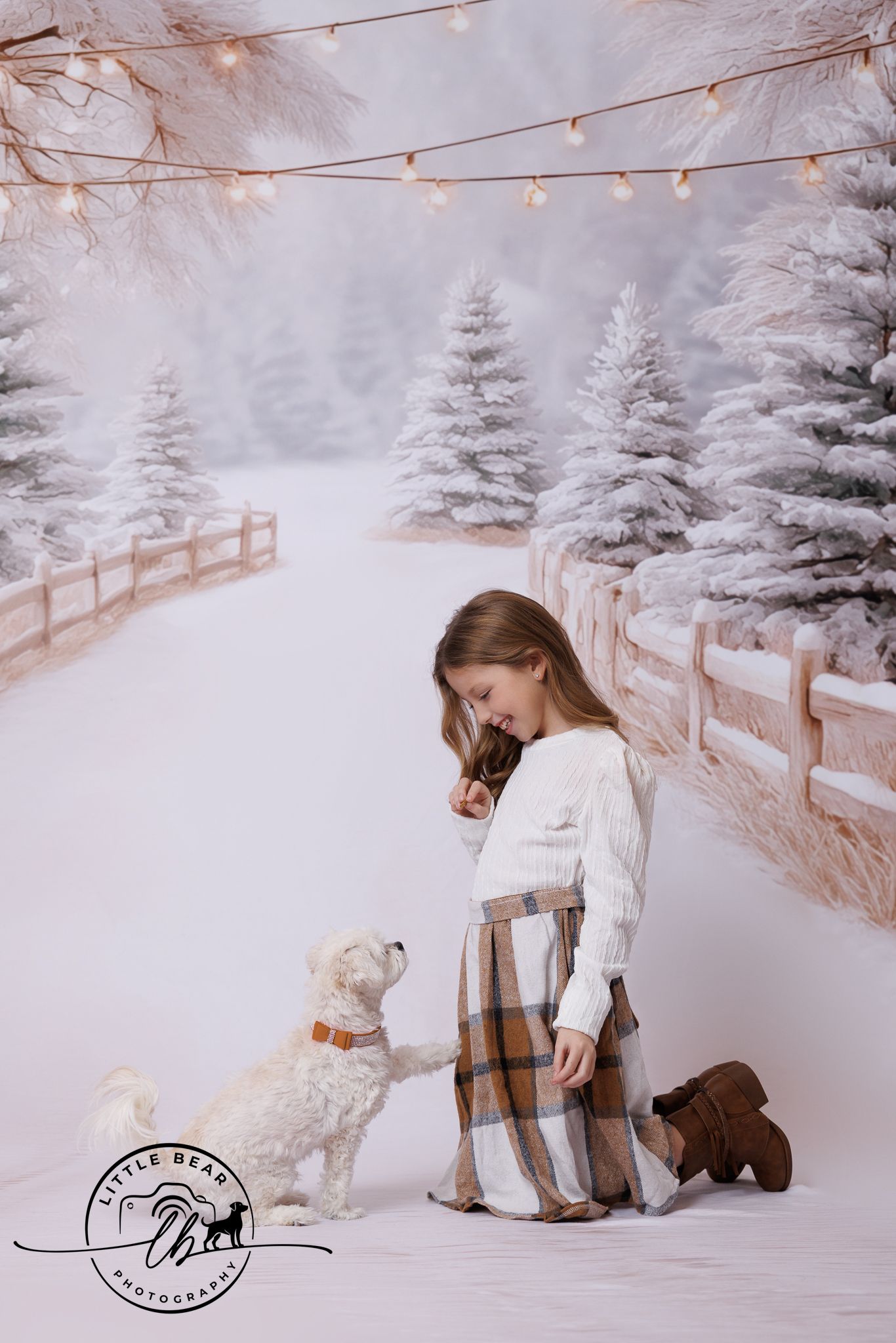 Girl in plaid skirt kneels in snowy winter scene with white fluffy dog and fairy lights backdrop.