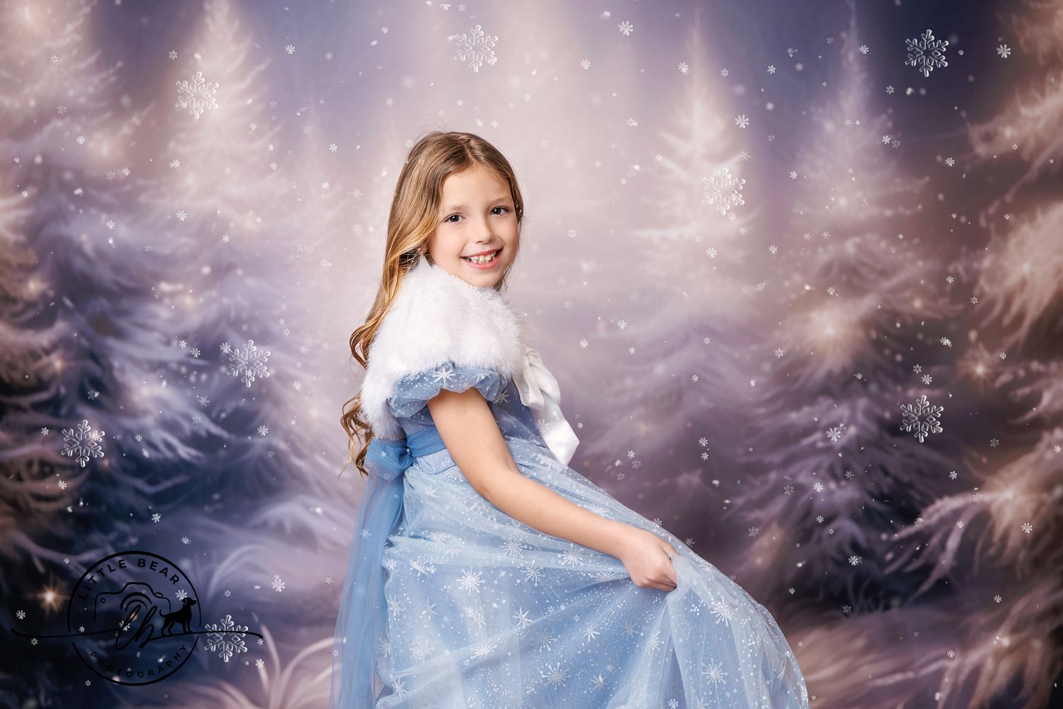 Young girl in blue Cinderella gown poses in magical snowy winter forest photography backdrop.