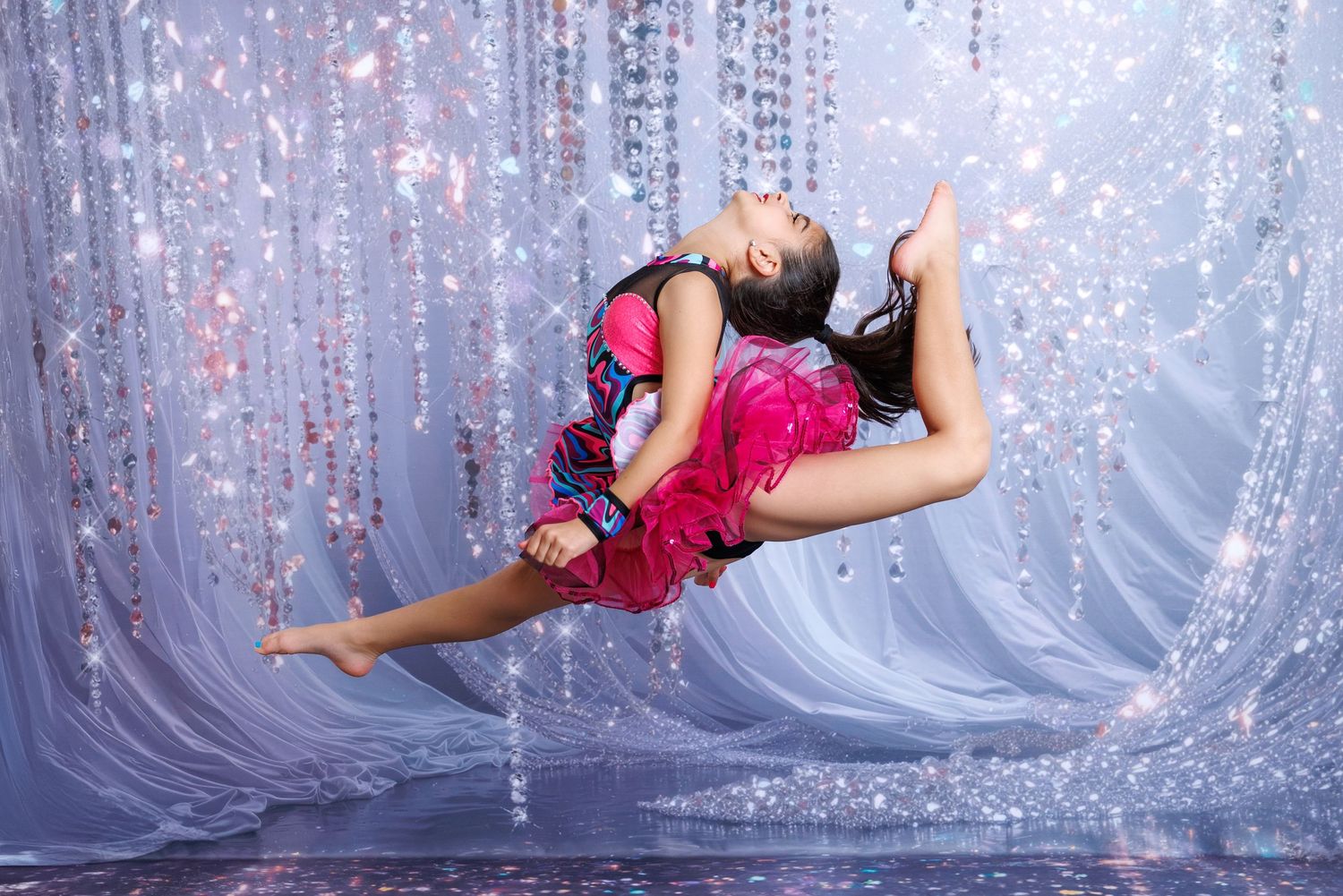 Young female dancer in pink costume performing a dramatic leap in front of sparkling curtain backdrop.