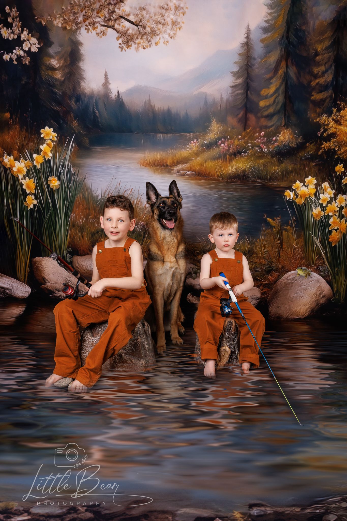 Two boys in orange overalls sitting with a German Shepherd dog by a daffodil-lined mountain stream.