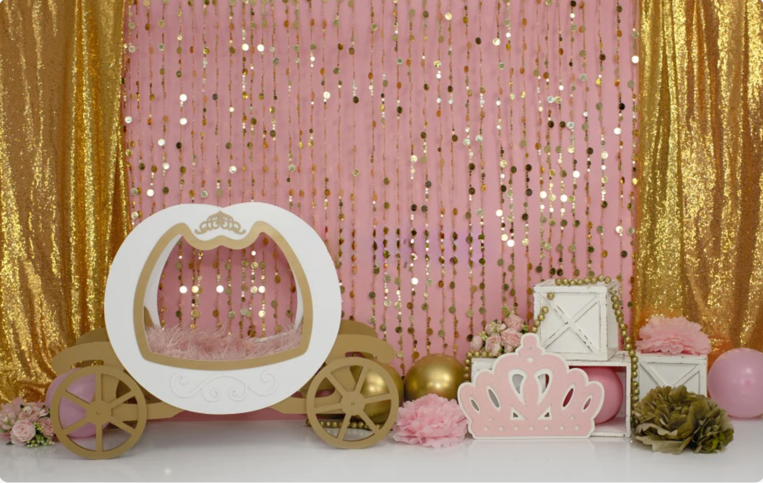Pink and gold princess carriage cake smash backdrop with sequin curtains, crown decor, and floral accents.