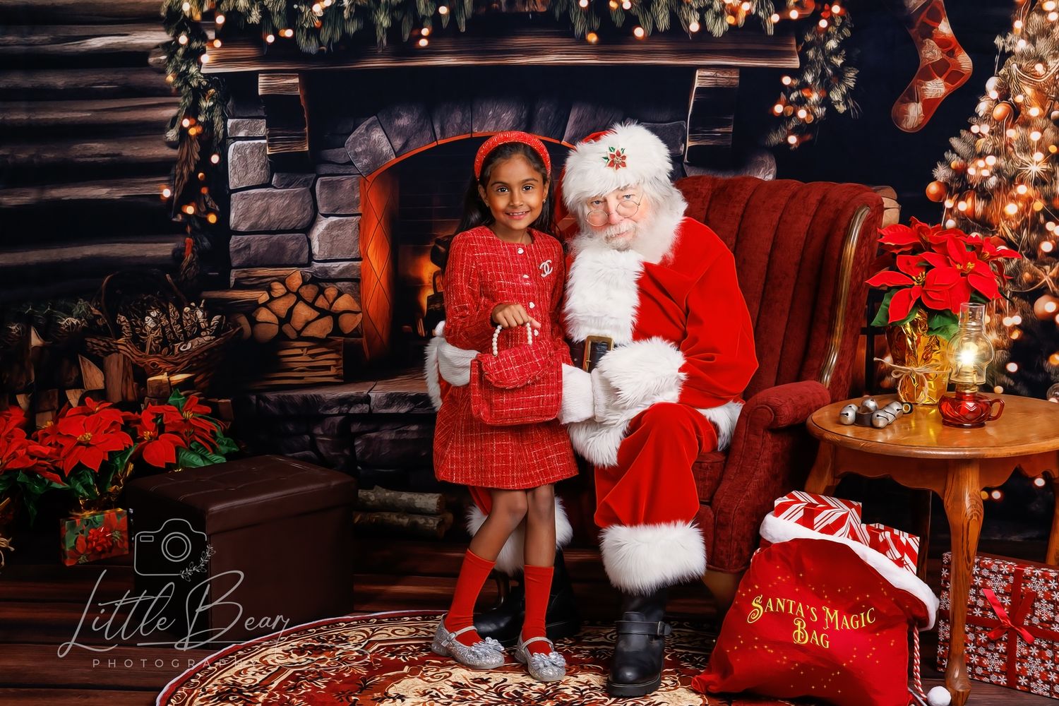 A young girl in red plaid dress poses with Santa Claus by a decorated fireplace and Christmas tree.