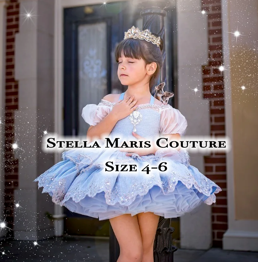 Young girl in blue Stella Maris Couture dress size 4-6 with crown tiara posing outdoors near brick building.