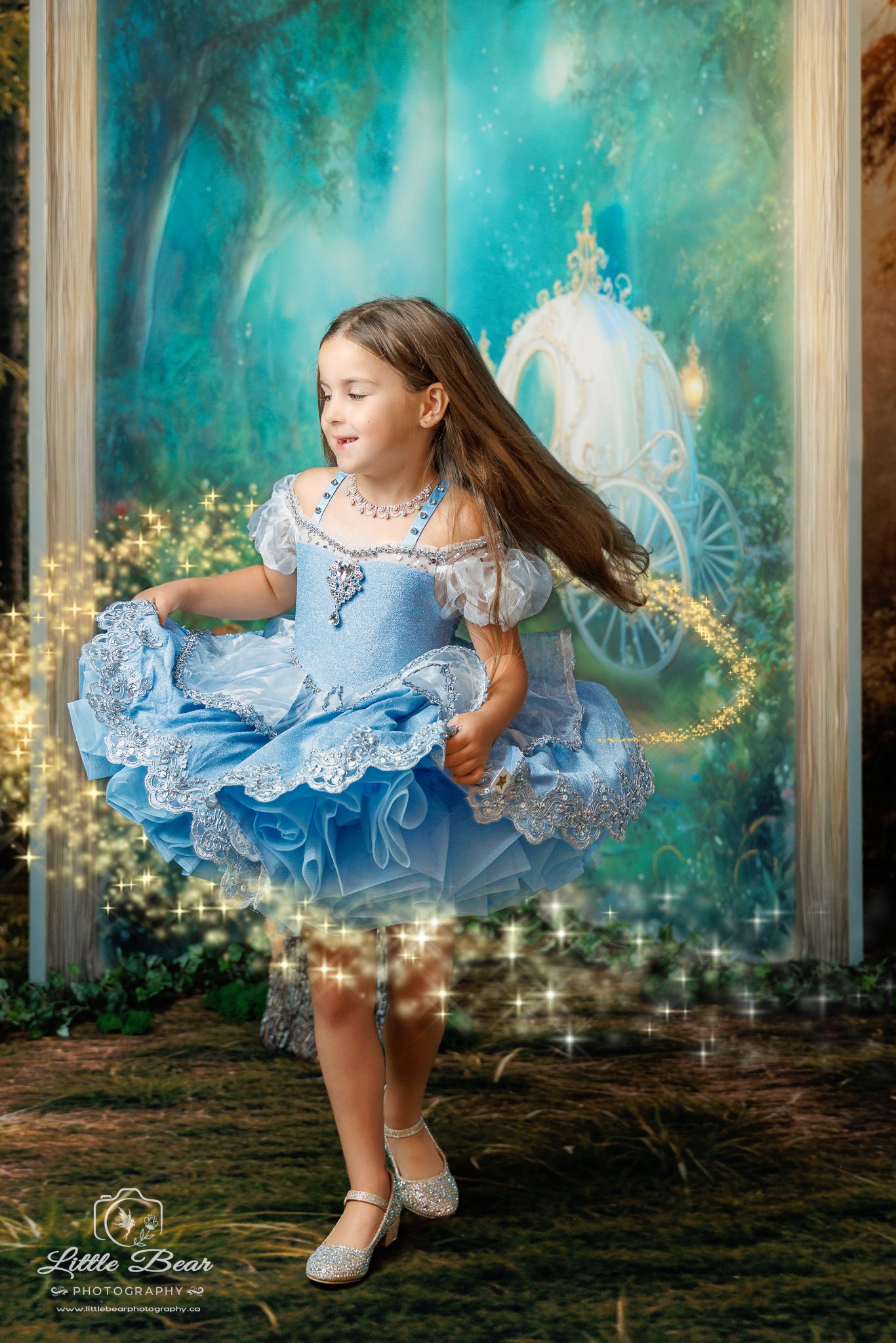 A young girl twirls in a blue Cinderella gown with sparkles and a fairy tale carriage backdrop.